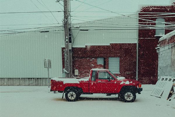 Red pickup truck parked outside a building